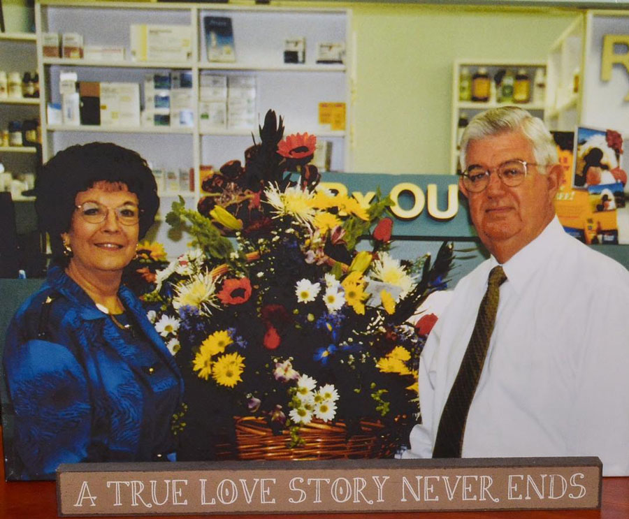 Jasper Drug Store owners smiling next to a bouquet of flowers.